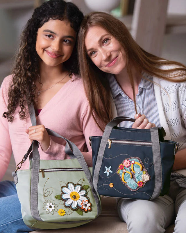 Two smiling women holding handbags