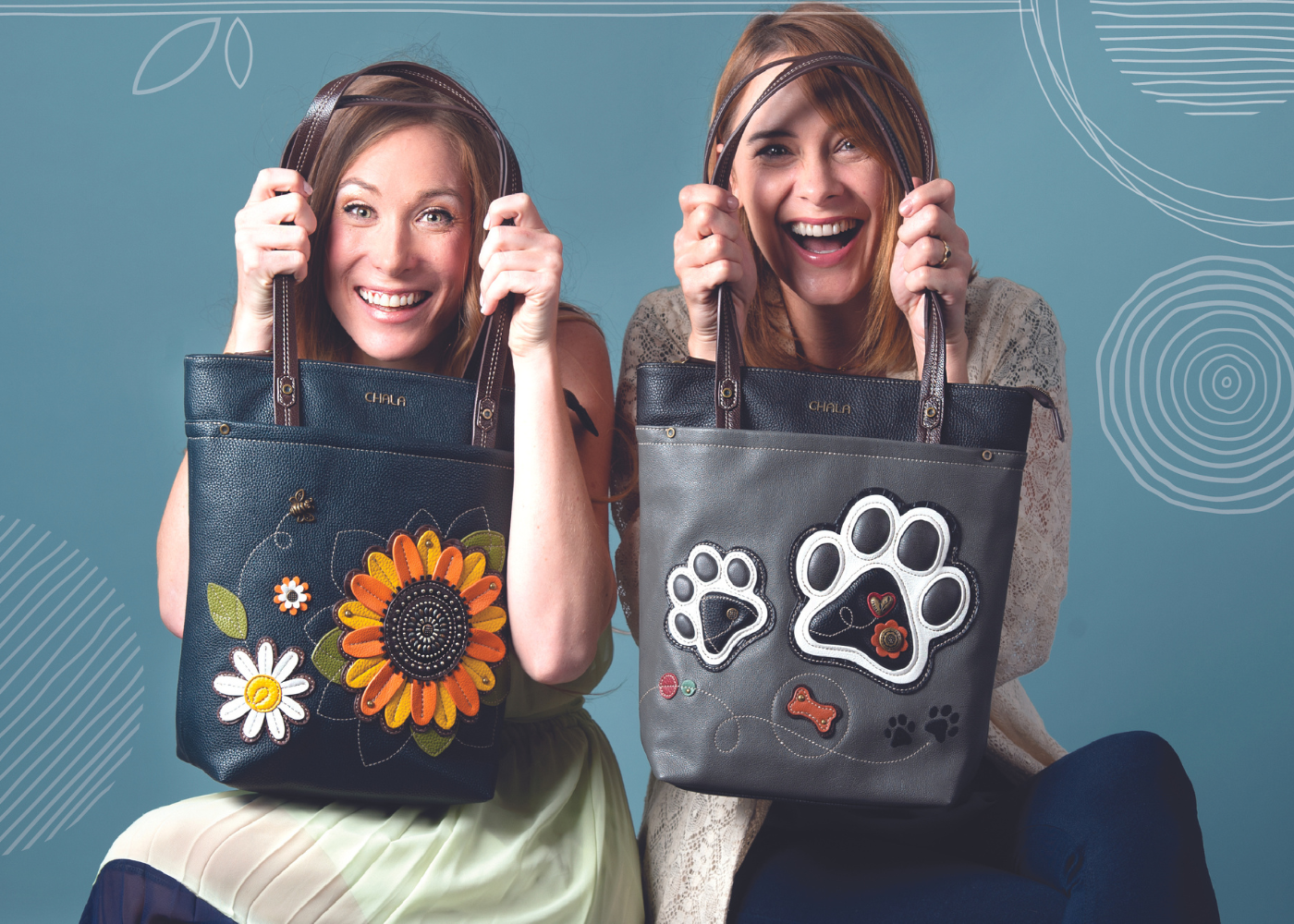 Two smiling women holding up handbags