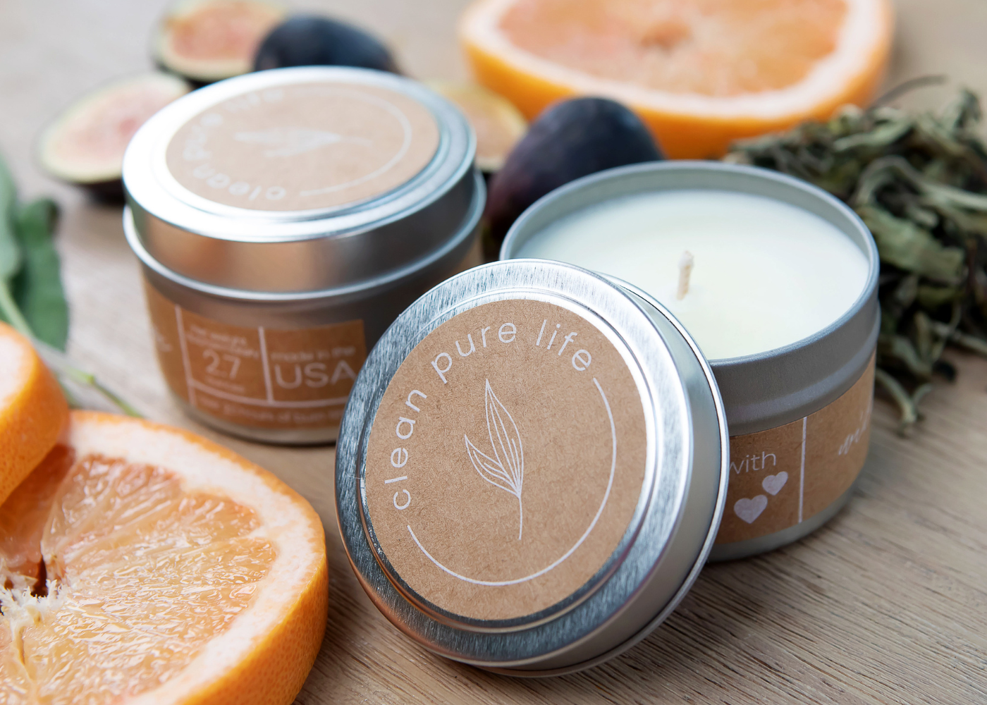 Two candles in tin holders surrounded by fruit