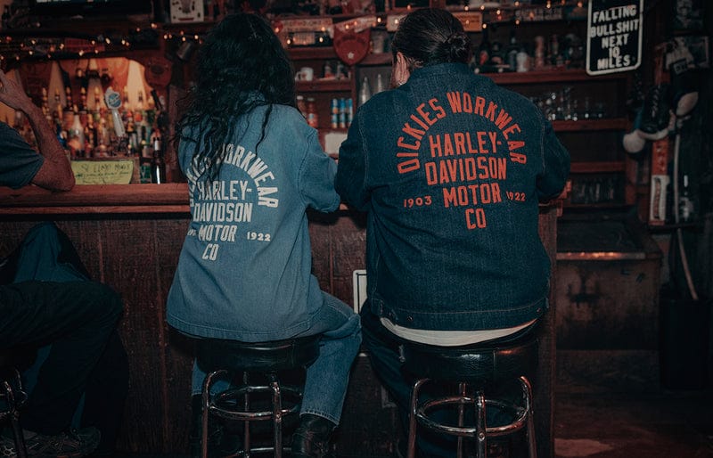 Two people wearing Harley-Davidson jackets sitting at a bar.