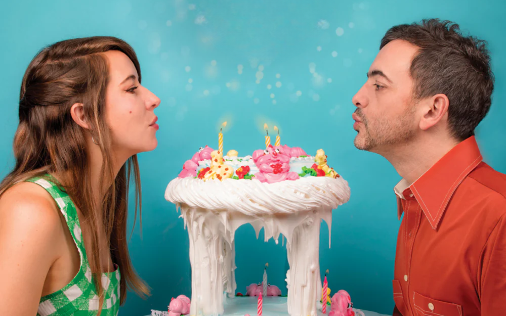 Man and woman blowing out birthday cake candles