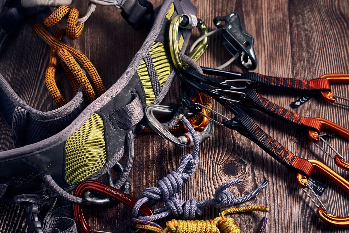 Rock climbing gear including a harness, ropes, and carabiners on a wooden surface