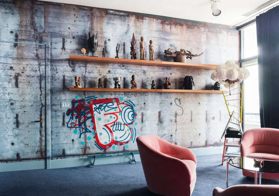 Modern interior with concrete wall, shelves with decorative items, and pink chairs.