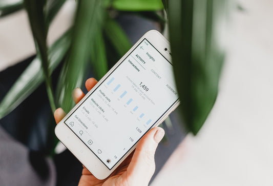 A hand holding up a mobile phone showing instagram interaction stats on the screen.