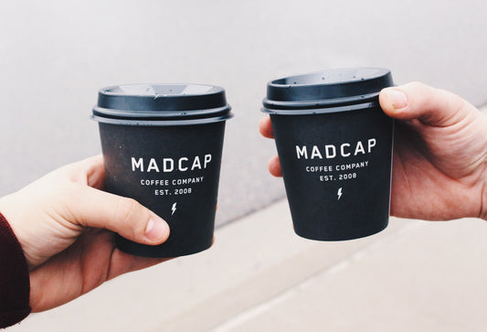 Two hands holding paper coffee cups.