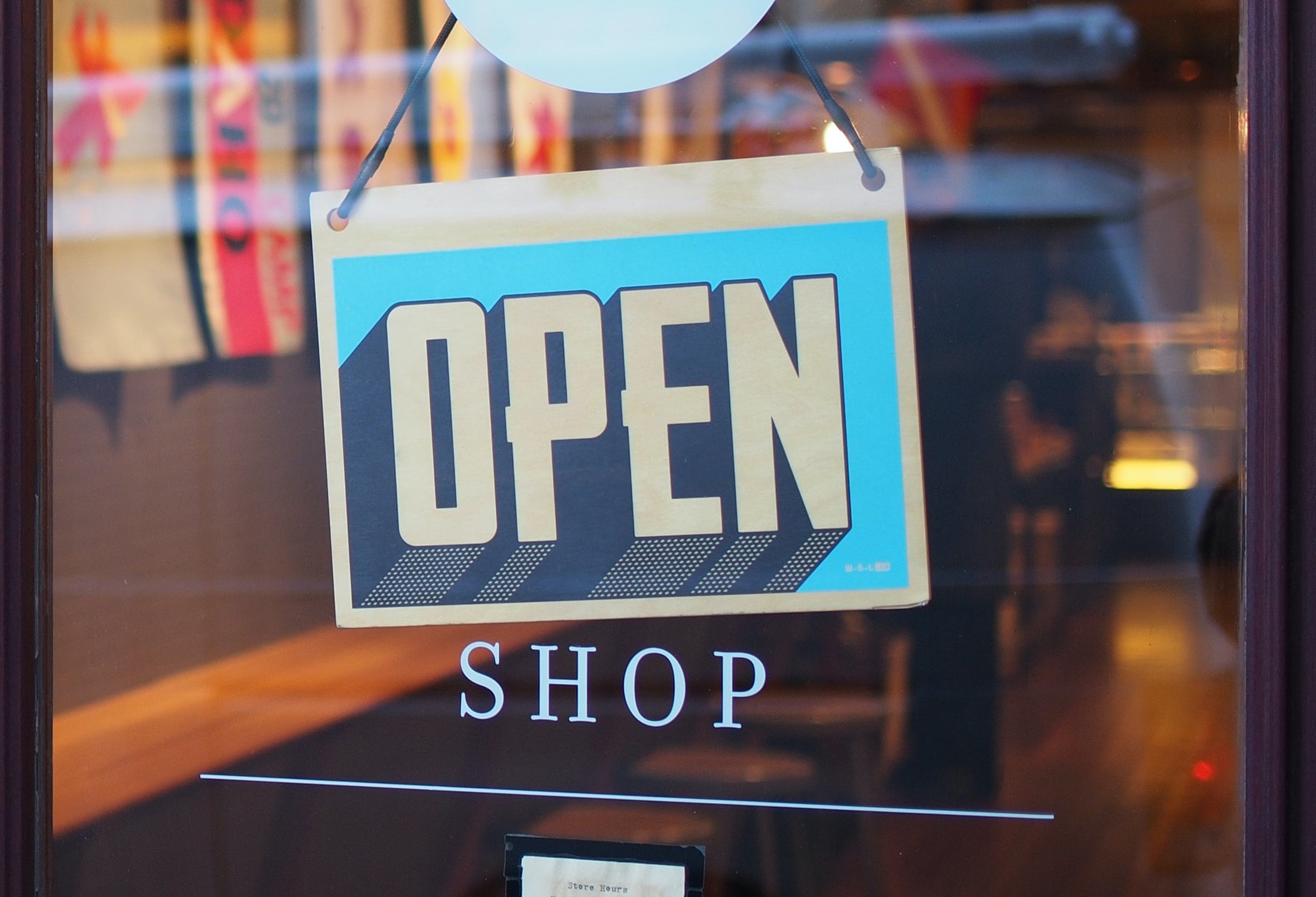 A open sign displayed over glass shop door.