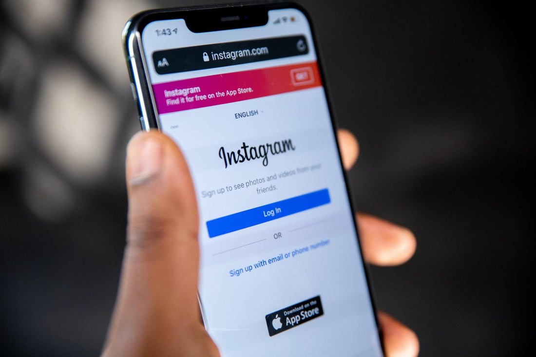 A hand holding up a phone with the Instagram login page on the screen.