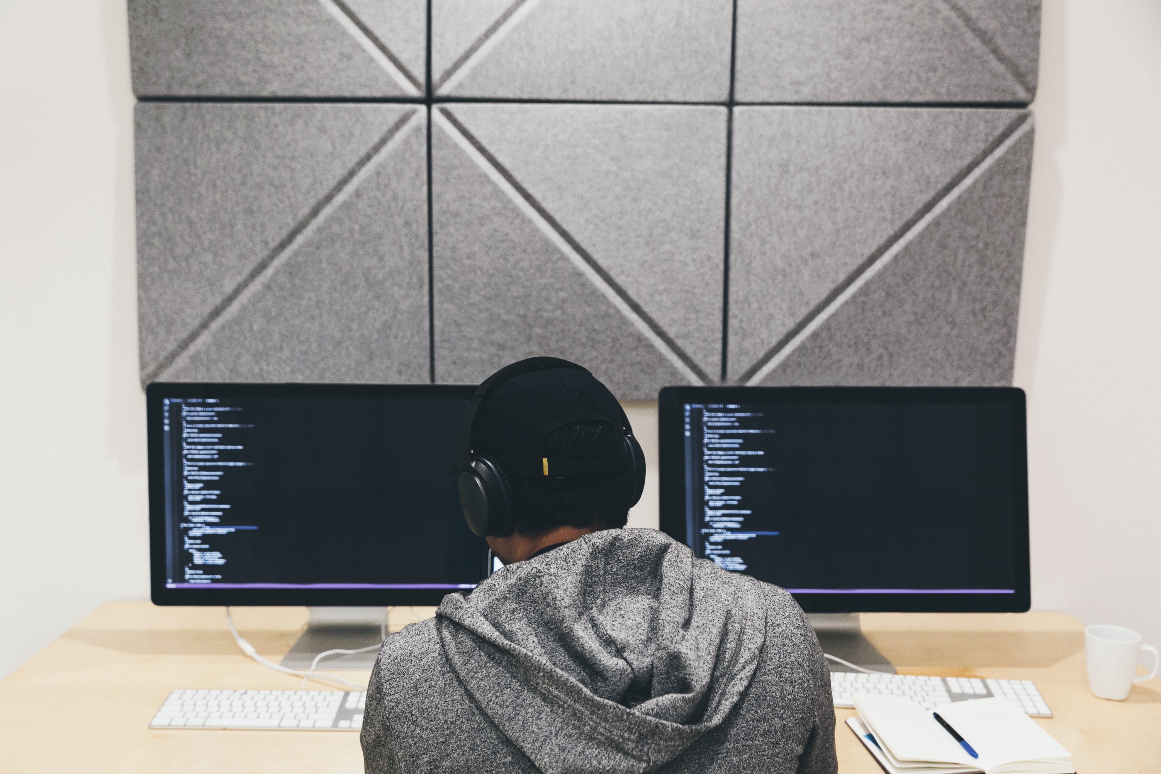 A programmer sitting in front of a computer screen intently focused on writing code. 