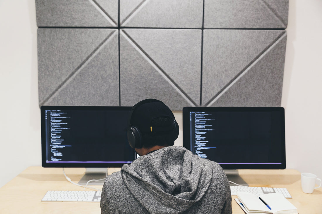A programmer sitting in front of a computer screen intently focused on writing code. 