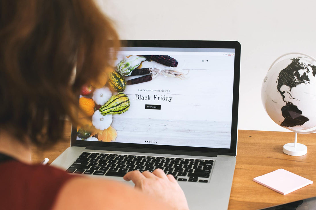 An over the shoulder look at a woman on her laptop viewing a hero image of a Black Friday sale