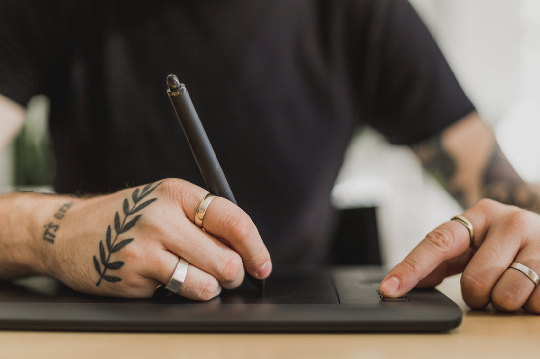A person's hands using a tablet device to edit or design something with a stylus pen.