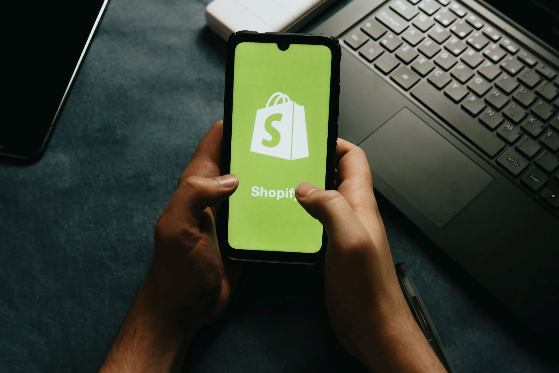 hands-holds-a-cell-phone-showing-the-shopify-logo